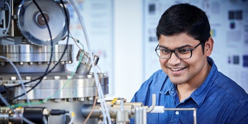 Person smiling, looking at scientific equipment