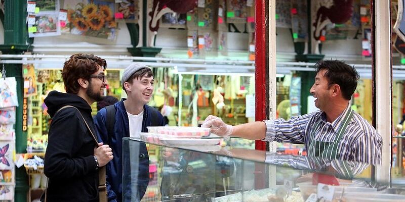 Two students chatting to a vendor in Kirkgate Market in Leeds