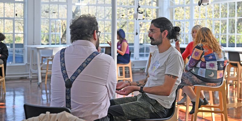 A bright and airy room, with several people in it, sat chatting in pairs