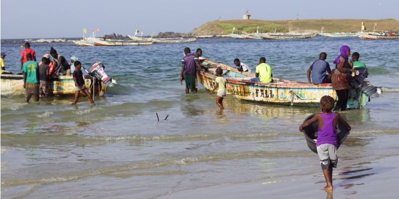 Villagers pushing small fishing boats out to sea on the coast of Dakar.