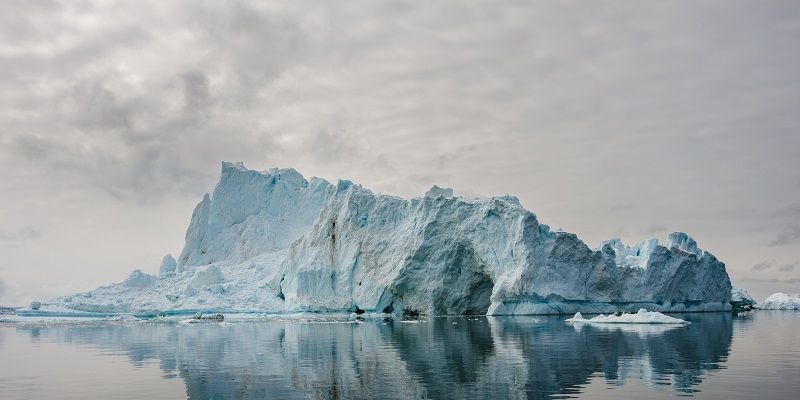 A large iceberg floating in the sea in Disko Bay, Greenland. The iceberg stands tall above the sea, posing a hazard to nearby maritime traffic