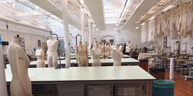 Fashion studio including mannequins, sewing machines and tables.