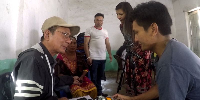 A group of Nepalese people examining filming equipment