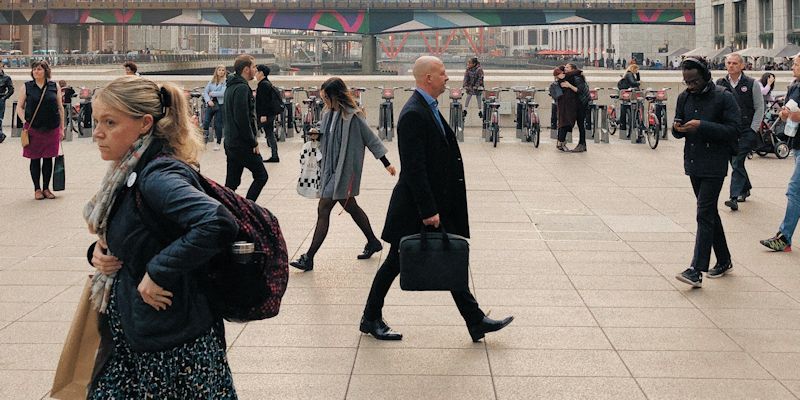 A busy footpath with lots of people walking in different directions in London on a cold day