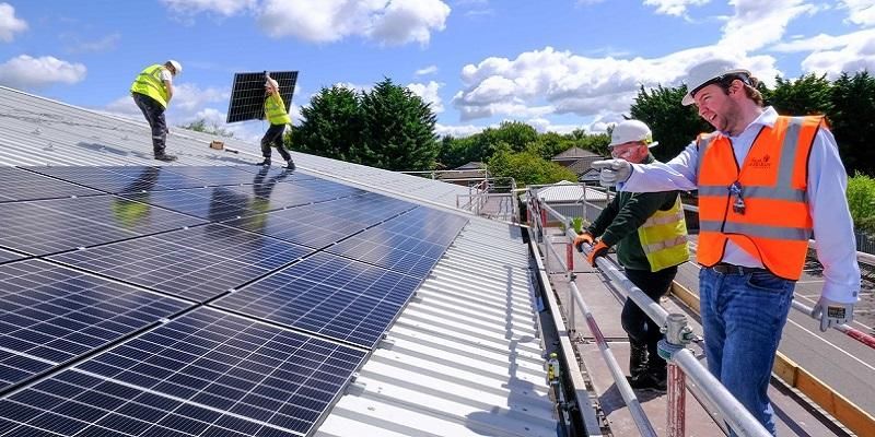 Workforce installing solar panels on a large roof