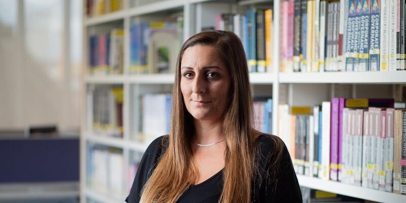 A mature student with shelves of books in the background