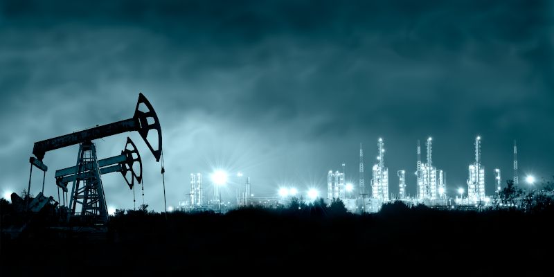 Oil rigs at night, with industrial towers lighting the background.