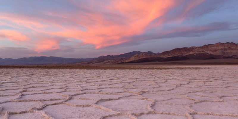 A dried-out salt lake in Death Valley, California at sunset, displaying the characteristic honeycomb-like patterns