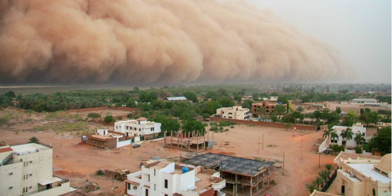 A village on the edge of a desert about to be engulfed by a sandstorm
