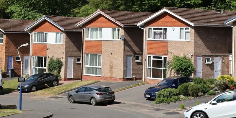 A row of newly built detached houses on a suburban street in the daytime.