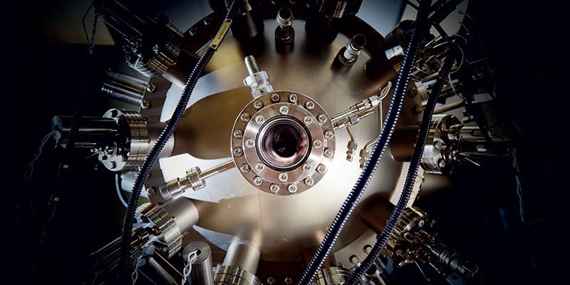 A photograph of the circular observation window in the vacuum chamber of the physical vapour deposition system in the Bragg Centre