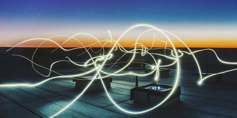 Squiggly lines of light over electrical boxes with sunset over horizon