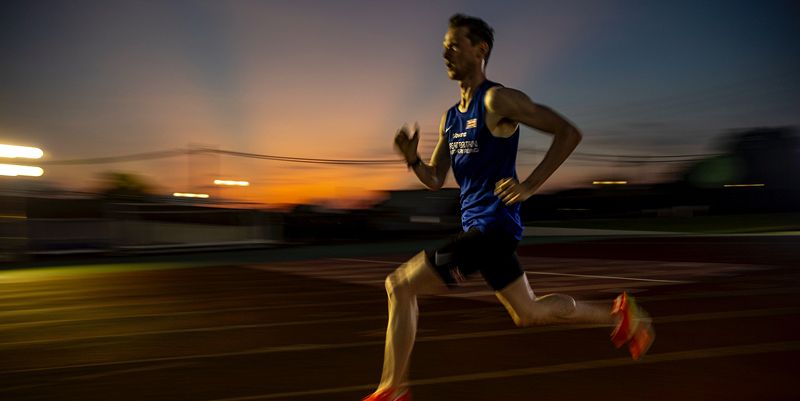 Max Burgin races around a running track as the sun sets behind him