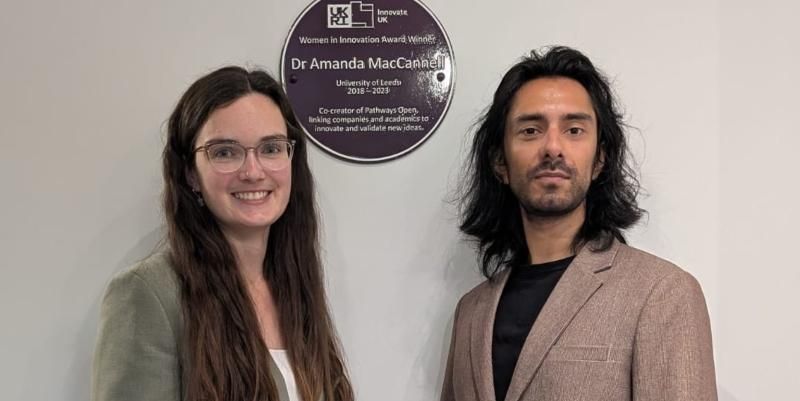 Amanda and Sandeep, co-founders of Pathways Open, stand in front of the purple plaque which recognises Amanda as a great innovator.