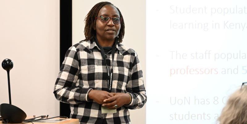 Professor Cecilia Onyango talking to an audience with a presentation slide behind. 