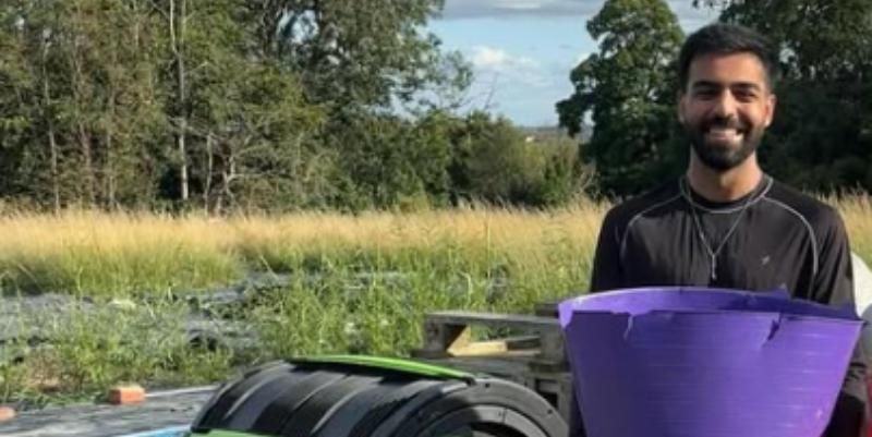 Husain stands in a field with a caddy to collect food waste