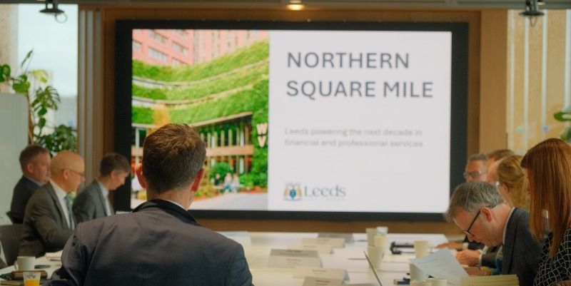 Meeting attendees view a presentation on the Northern Square Mile initiative in Leeds. Large presentation screen displays the title “Northern Square Mile”.