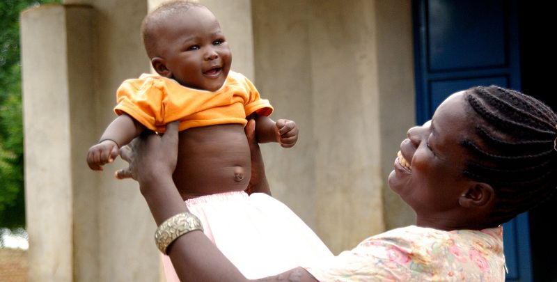 A mother is proudly holding a baby up in her arms.