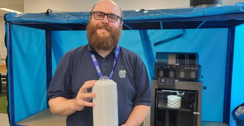 Ben Pickering stands holding the camera he has built to enhance weather forecasting from local weather stations.