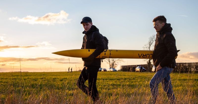 LURA founder Theo Youds and Chief Engineer Dominykas Buta carry the Gryphon I-C out to the launch station through a field at sunset