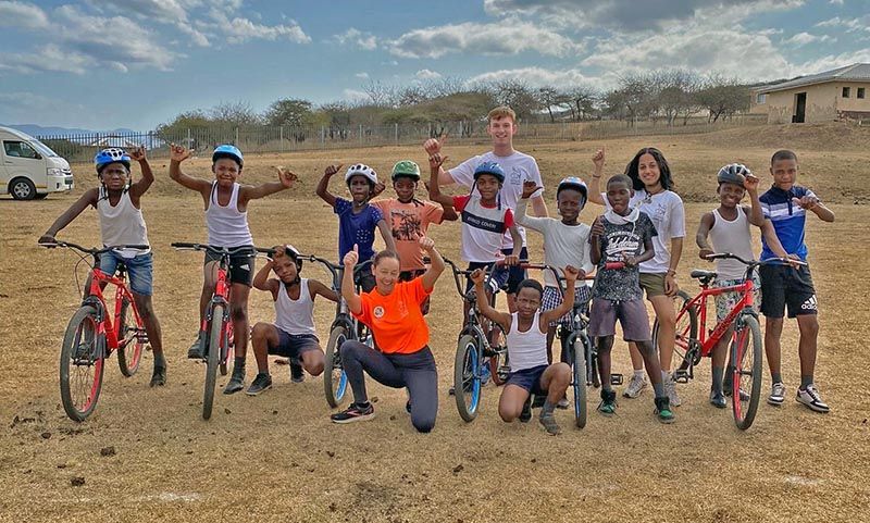 Tracy with a group of young people and their bikes. They are cheering.