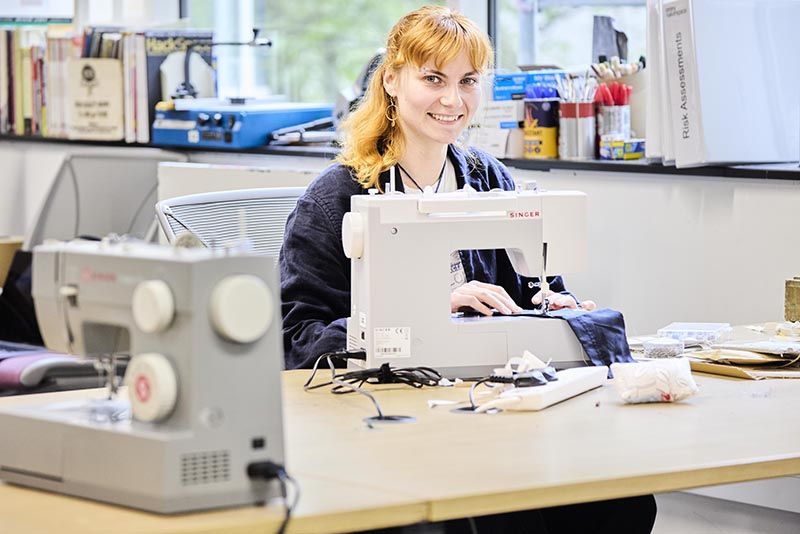 Eleanor Smith sat at a desk using a sewing machine.