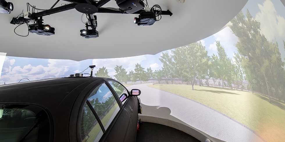 Inside a driving simulator, showing a vehicle and computer generated view of a road