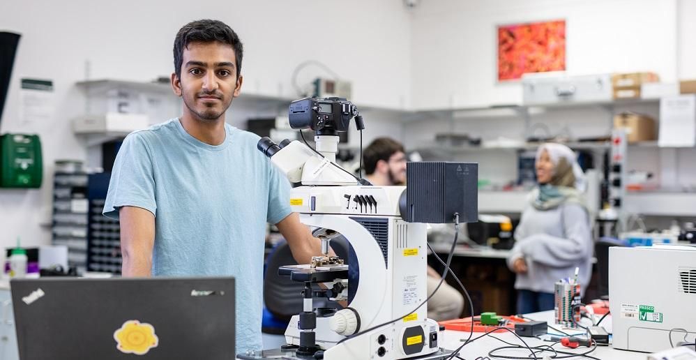 postgraduate researcher at laptop in lab