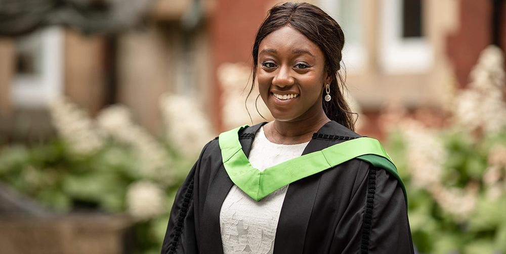 A graduate smiling and wearing a gown on graduation day