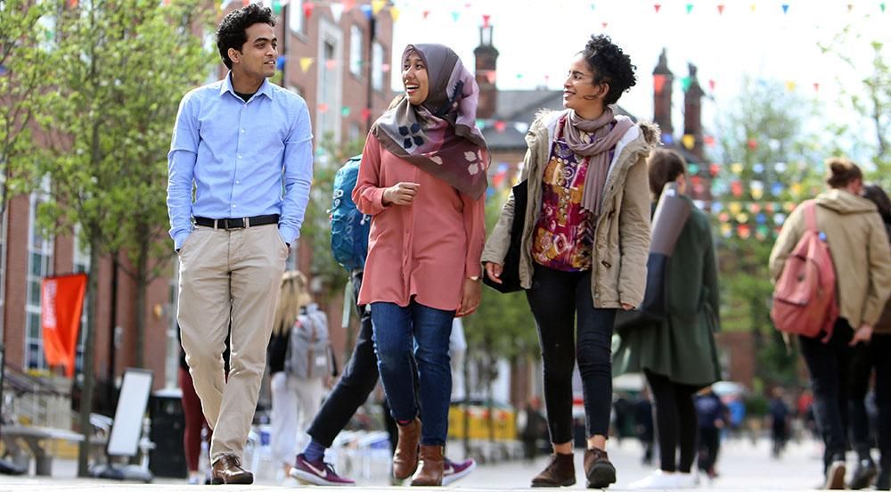 Three students walking together outside Leeds University Union.