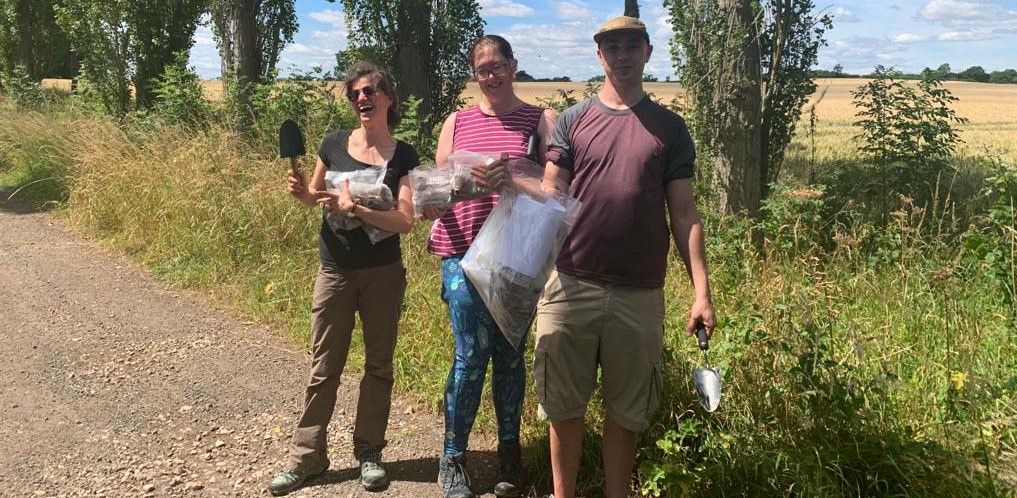 Dr Elder (centre) pictured in the countryside with two others in the team holding trowels and bags of soil samples