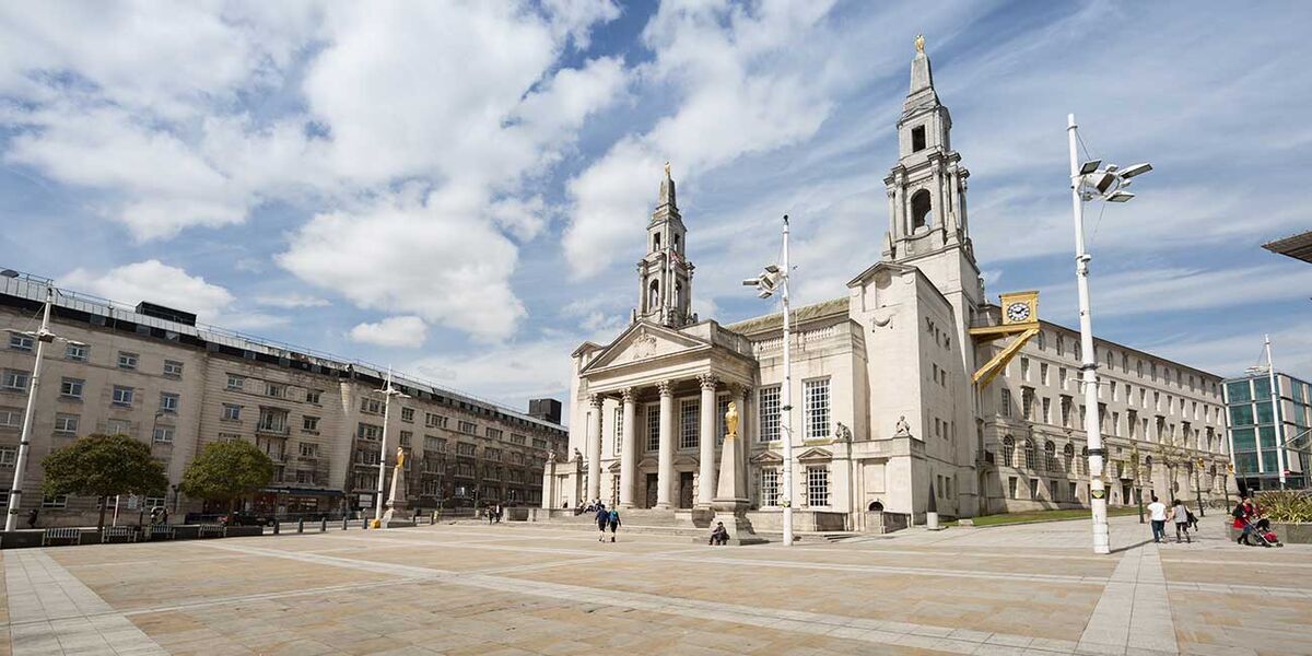 Leeds Civic Hall, a large white stone building with two towers. Millennium Square is in the foreground.