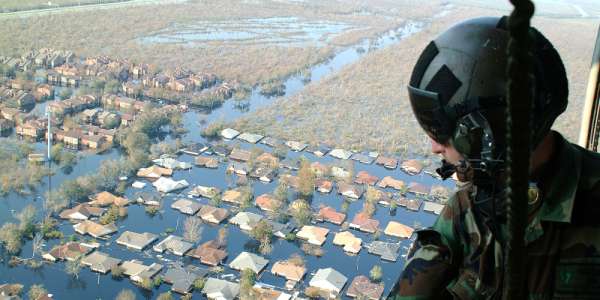 Support worker looks out of helicopter onto flooded town