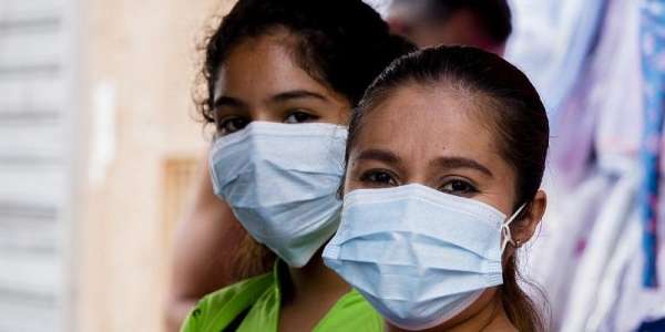 The image is a close up of two women wearing face masks, presumambly to stop them spreading or contracting the coronavirus