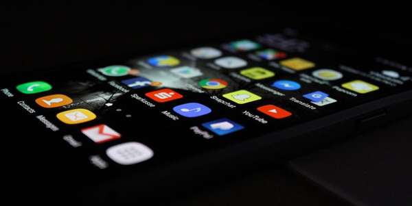 A smartphone on a black background with various apps on its screen.
