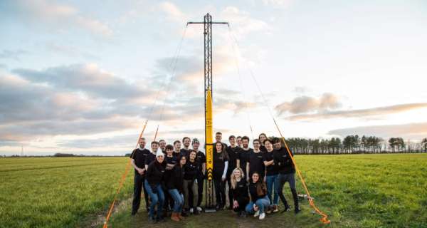 The Leeds University Rocketry Association stand in a field beside their first rocket
