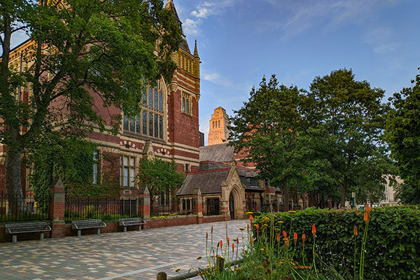 A side shot of the Great Hall in summer with flowers in the foreground and the Parkinson tower in the background