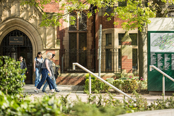 Students walking and talking outside the Great Hall in summer.