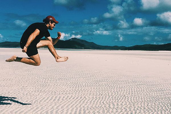 Ben Barrett jumping in the air on a beach