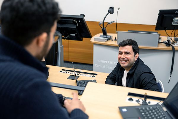 A member of University of Leeds staff smiling in a lecture theatre.
