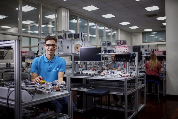 Student Jefferson Sanchez in the National Instruments Active
Learning Laboratory. Staff are working with robotics in the background.