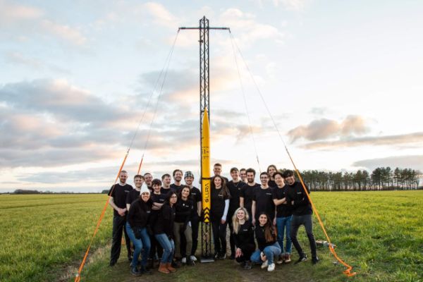 The Leeds University Rocketry Association stand in a field beside their first rocket