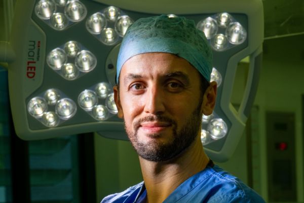 Moez Zeiton wears surgical gown and headwear in surgery
