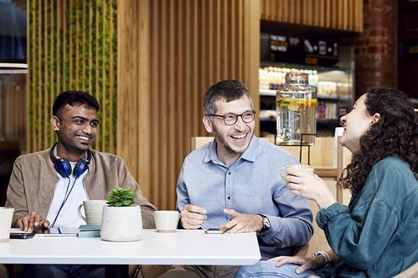 Three people sitting in a cafe talking and laughing