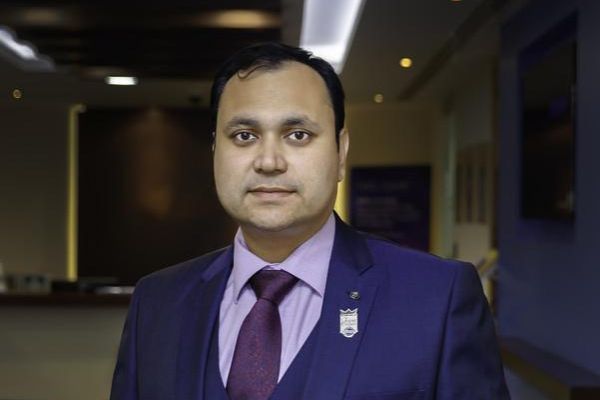 Leeds alumni community member, Sandeep Kinge, wearing a suit and purple shirt and tie.