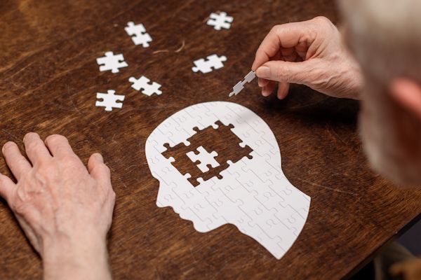 Senior man completes a brain shaped jigsaw.
