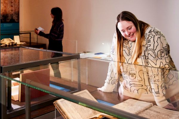 A person looking through a glass cabinet at rare items in the galleries.