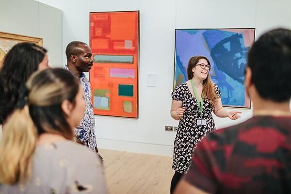 A member of staff talking to a group in front of a painting in the Stanley and Audrey Burton Gallery.