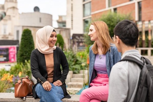 Three students chatting in the city centre.