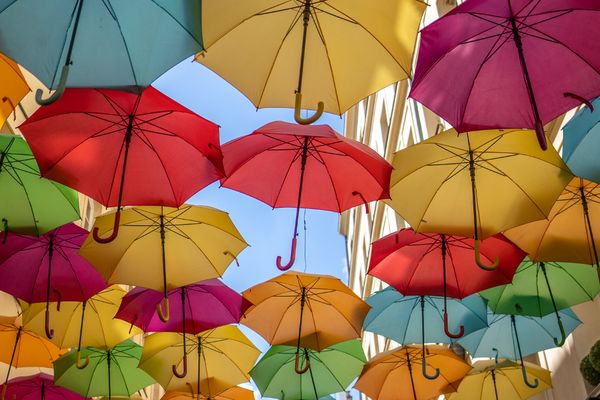 Multiple colour umbrellas under a blue sky